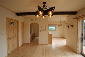 白い塗壁とナチュラルな無垢フロアーが爽やかな室内。ダイナミックな梁とお洒落なシャンデリアが良いアクセントに。